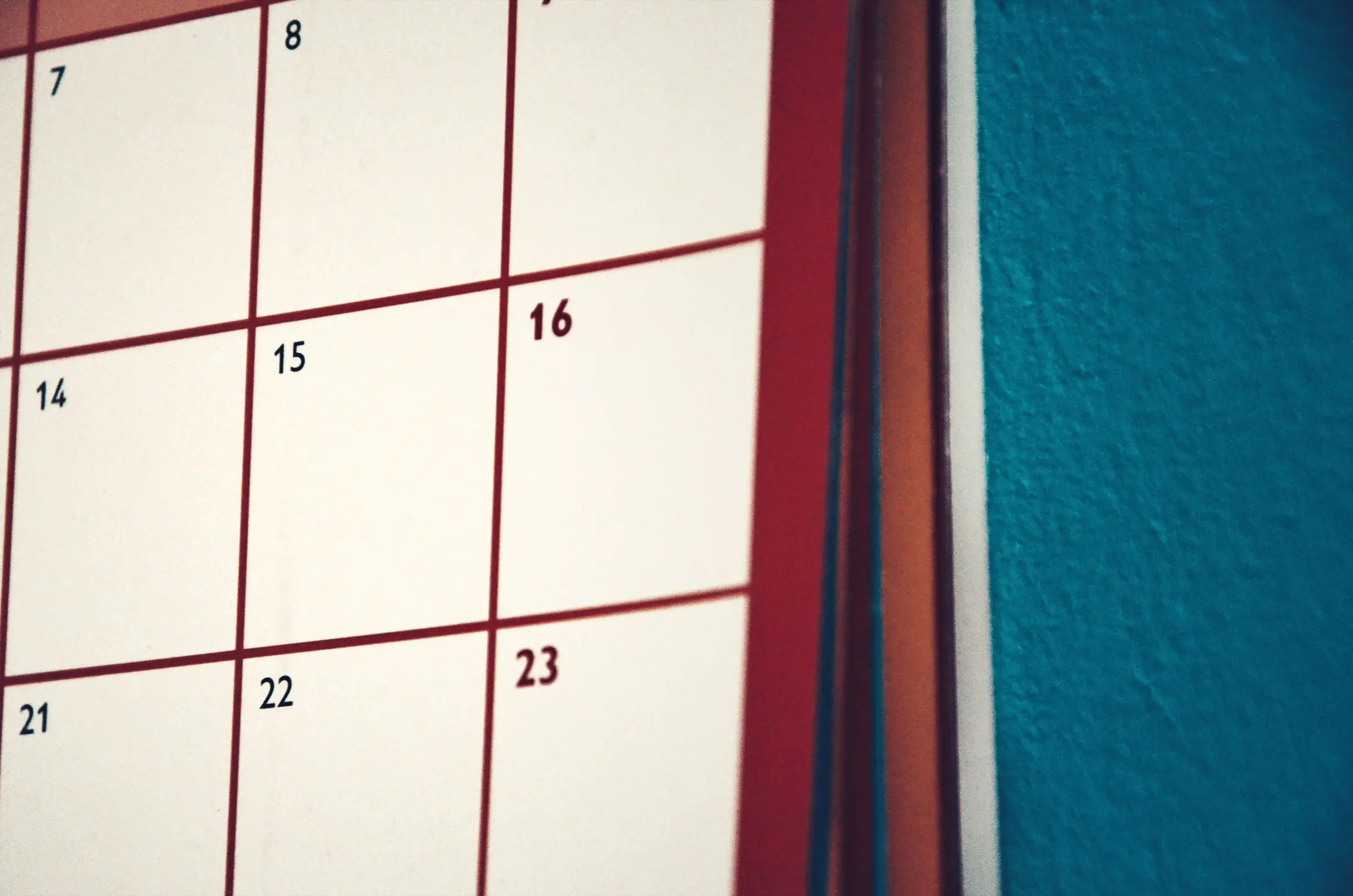 Close-up of a wall calendar beside a teal wall